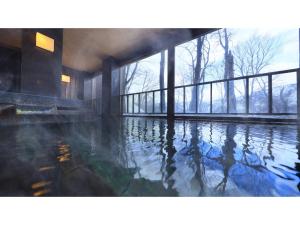 青森Sukayu Onsen Hakkoda Hotel - Vacation STAY 66845v的一座带窗户的建筑里的一个水池