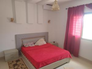 Awlād ‘UmarVilla Château D'eau Djerba的一间卧室配有一张带红色棉被的床和窗户。