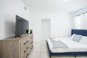 迈阿密Modern 3-Bedroom in the Heart of Wynwood Art District的一间卧室配有一张床,梳妆台上配有电视