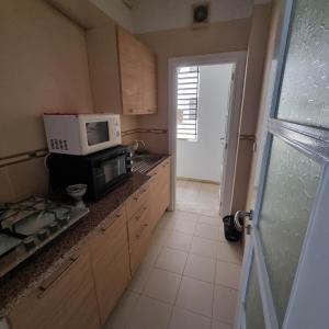 艾尔亚奈City View, Ennasr Spacious s2 Apartment的带微波炉的厨房,位于带窗户的柜台上