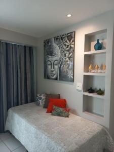 福塔莱萨LIV INN Apartamento na Beira-Mar Fortaleza的卧室配有一张床铺,墙上挂着雕像