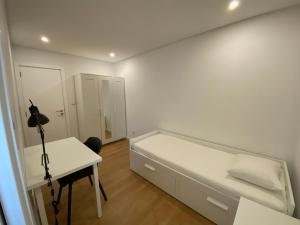奥埃拉斯Carcavelos Beach Walking distance room的白色卧室配有床和书桌