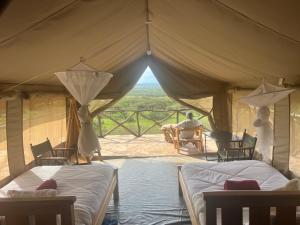 NarokSunset camp的帐篷配有两张床,还有一人坐在桌子上