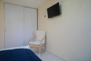 奥拉涅斯塔德Pavia's Centerpoint Oasis的一间卧室配有一张床、一把椅子和电视。