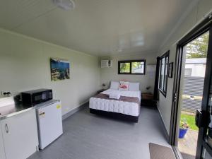 卡塔尼Whakatane Holiday Park的一间带床和冰箱的小卧室