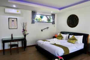 拉威海滩Jasmine Village的一间卧室配有一张床、一张桌子和一个窗户。