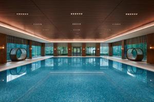 昌平北京乐多港万豪酒店的一座大型游泳池,位于一座带窗户的建筑内