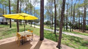 磅士卑省Romdoul Kirirom Resort的甲板上黄色遮阳伞下的桌椅