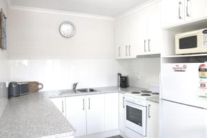 梅林布拉Calendo Apartments的白色的厨房,配有白色家电和墙上的时钟