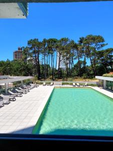 埃斯特角城Moderno Apartamento #1 Excelente ubicación的一座带椅子和树木的建筑中的游泳池