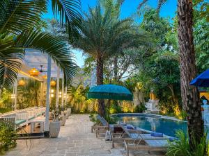 坎古巴厘梦幻别墅回声海滩加努度假酒店的一个带椅子和遮阳伞的游泳池以及棕榈树