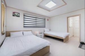 仁川市哈布旅馆的一间白色卧室,配有两张床和窗户