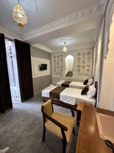 布哈拉AL-HAYAT的酒店客房带两张床和一张桌子以及椅子。