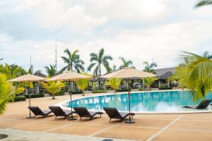 BugallonRiver Palm Hotel and Resort powered by Cocotel的度假村的游泳池,配有椅子和遮阳伞