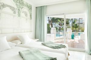 马贝拉Iberostar Selection Marbella Coral Beach的卧室设有两张床,享有庭院的景色