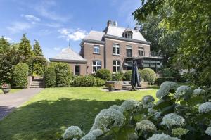 埃滕-勒尔Stylish Guesthouse with 2 Free E-bikes - near Breda!的一座大房子,带鲜花的院子