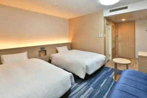 名古屋名古屋荣华盛顿广场酒店的酒店客房,设有两张床和一张蓝色的沙发