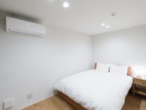 萩市Rakuten STAY HOUSE x WILL STYLE Hagi Nishitamachi的卧室配有白色的床和白色的墙壁