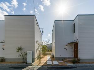 萩市Rakuten STAY HOUSE x WILL STYLE Hagi Nishitamachi的两座白楼,两楼之间阳光灿烂
