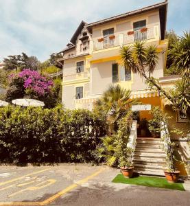 塞勒里古Hotel Arcobaleno的一座黄色的建筑,前面有楼梯和植物