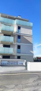 琴斯托霍瓦Apartamenty 77的白色的建筑,旁边标有标志