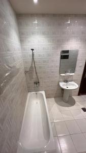 Al ḨawīyahRadiha Hotel Suites的白色的浴室设有浴缸和水槽。