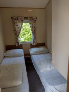 斯沃尼奇Swanage Coastal Park Hideaway的小型客房 - 带2张床和窗户