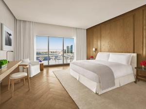 阿布扎比The Abu Dhabi EDITION的卧室配有白色的床、书桌和窗户。