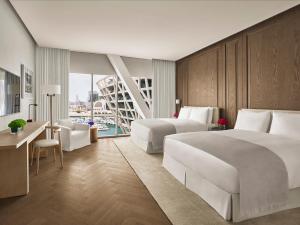 阿布扎比The Abu Dhabi EDITION的酒店客房配有两张床、一张书桌和一张书桌。