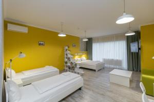 利沃夫Opera Passage Hotel & Apartments的客厅配有2张白色沙发和1面黄色的墙壁