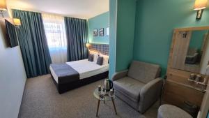 瓦尔纳阿奎亚酒店的配有一张床和一把椅子的酒店客房