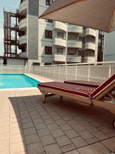 米兰马瑞提那MARITTIMO Milano Marittima的游泳池旁的长凳,带建筑物