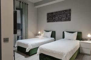 塔什干Sapiens Hotel的配有白色床单的酒店客房内的两张床