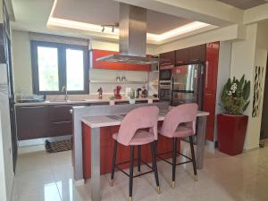 哈拉奇Villa Maria的厨房位于厨房岛,配有粉红色凳子