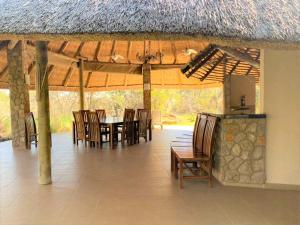 布拉瓦约Twin bed lodge on natural African bush - 2111的一个带桌椅的用餐区以及茅草屋顶