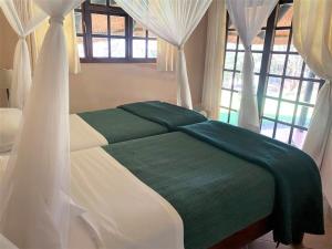 布拉瓦约Twin bed lodge on natural African bush - 2111的一间卧室配有绿白色的床和窗帘