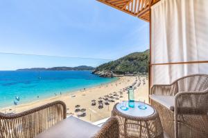 圣胡安包蒂斯塔El Somni Ibiza Dream Hotel by Grupotel的享有海滩美景,配有椅子和桌子