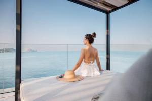 圣何塞7Pines Resort Ibiza, part of Destination by Hyatt的坐在床上看着大海的女人