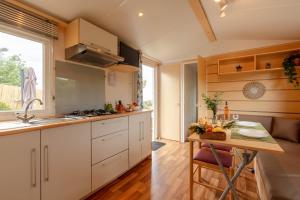 耶尔Le Photinia, mobil-home climatisé avec vue mer situé au cœur du domaine的厨房配有白色橱柜和木桌