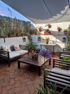 赫雷斯-德拉弗龙特拉La Gitanilla Alojamiento & Encanto Jerez的天井配有沙发、桌子和盆栽植物