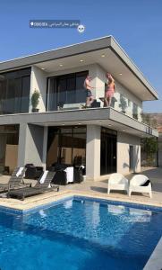 索瓦马Follow Sea Villa的两人站在带游泳池的房子的阳台上