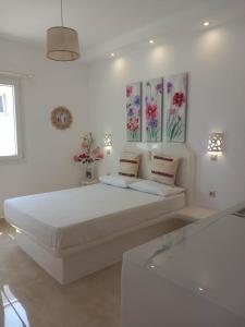 阿吉奥斯普罗科皮奥斯克里马塔利亚公寓的白色卧室设有一张墙上鲜花的大床