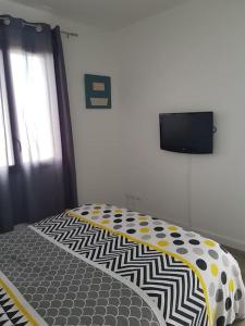 圣塞勒莱斯维Mini villa 84 sur la route des vins的卧室配有一张床铺,墙上配有电视