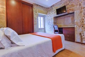查韦斯Alojamento Central的一间卧室设有一张床,石墙上配有电视。