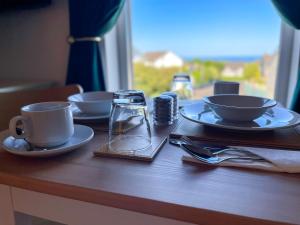 库申多尔Mount Edwards Hill Guest Accommodation的木桌,盘子,杯子,咖啡杯