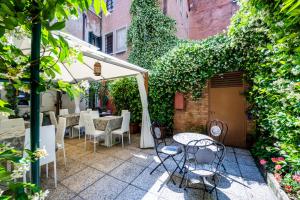 威尼斯Hotel Apostoli Garden的室外庭院配有桌椅和常春藤