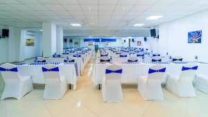 蒙巴萨Hotel Sapphire的宴会厅配有白色的桌子和蓝色的椅子