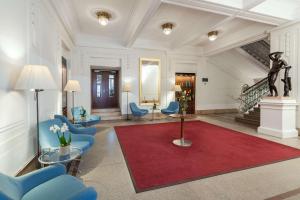 维也纳维也纳贝尔韦代雷NH酒店的大堂设有蓝色椅子和红色地毯