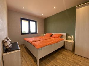 尼德根Ferienwohnung Am Weiher Kategorie 2的一间卧室配有带橙色枕头的床和窗户。