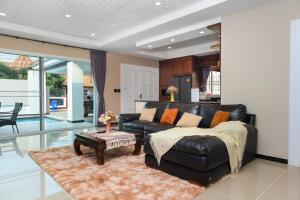 南芭堤雅CityHouse-OSCAR,pool villa 4Bedrooms-Jacuzzi-walking Street 10min的客厅配有真皮沙发和桌子